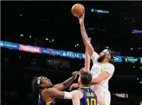  ?? Mark J. Terrill/Associated Press ?? Los Angeles Lakers forward Anthony Davis, right, shoots as Golden State Warriors forward Kevon Looney, left, and guard Ty Jerome defend during the first half on Thursday in Los Angeles.