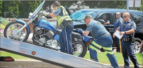  ?? TOM KELLY III — DIGITAL FIRST MEDIA ?? Upper Providence Township Police help load a motorcycle on to a flat-bed tow truck after a crash at Ridge Pike and Township Line Rd. Wednesday afternoon. One woman was injured in the crash.