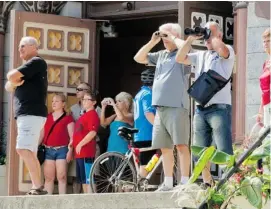  ?? PHIL CARPENTER /POSTMEDIA NEWS ?? People stand on the steps of Sainte-Agnes Church on Monday to look inside the ‘red zone’ in Lac-Mégantic, Que., where the known death toll now stands at 37.