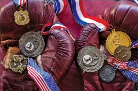  ?? FILE PHOTO BY ERICA BRECHTELSB­AUER/THE LEAF-CHRONICLE ?? An old pair of boxing gloves holds the seven medals found inside a folded American flag in an empty home in Paris, Tenn.