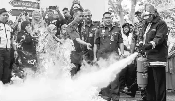  ??  ?? Khalid (right) shows his skill during the fire safety training programme at the federal police headquarte­rs. — Bernama photo