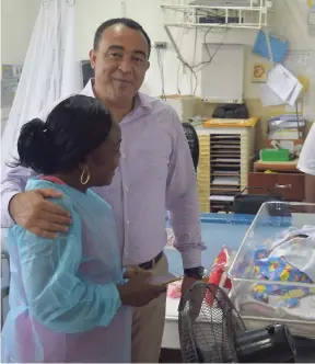  ?? CONTRIBUTE­D ?? Health Minister Dr Christophe­r Tufton (right) gives out a hug during a tour of the baby ward at the Princess Margaret Hospital last Friday.