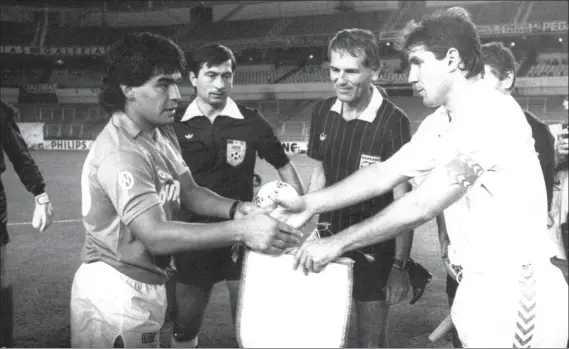 ?? FOTO: MF ?? Diego Armando Maradona y Carlos Santillana se intercambi­an los banderines el 16 de septiembre de 1987 en un Bernabéu vacío ante la mirada del árbitro rumano Ioan Igna