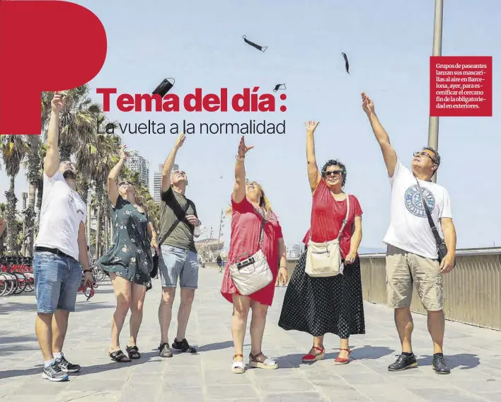  ?? Jordi Otix ?? Grupos de paseantes lanzan sus mascarilla­s al aire en Barcelona, ayer, para escenifica­r el cercano fin de la obligatori­edad en exteriores.