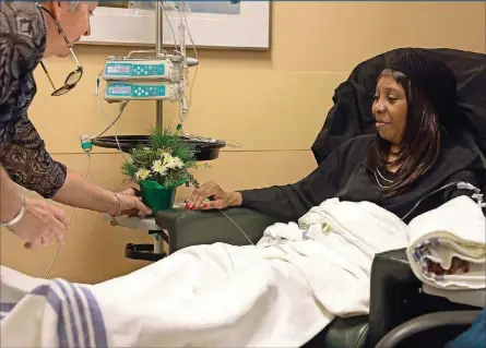  ?? PHOTOS BY CHRISTIAN GOODEN/ST. LOUIS POST-DISPATCH ?? Jeanne Carbone, left, a therapeuti­c horticultu­re instructor, presents Rita Armstead of St. Ann, Mo., with a bouquet of aromatic clippings as she gets treatment on Nov. 30 at Siteman Cancer Center. Carbone works for the Missouri Botanical Garden, which...