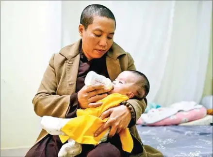  ?? TUOITRE.VN/VNS ?? Thich Minh Tai feeds An with a bottle of milk in their room at the pagoda.