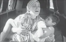  ?? Hussein Malla Associated Press ?? A SYRIAN WOMAN cries as she carries her son, who was shot in the hand by the Syrian border guard as they were crossing into Lebanon at Wadi Khaled.