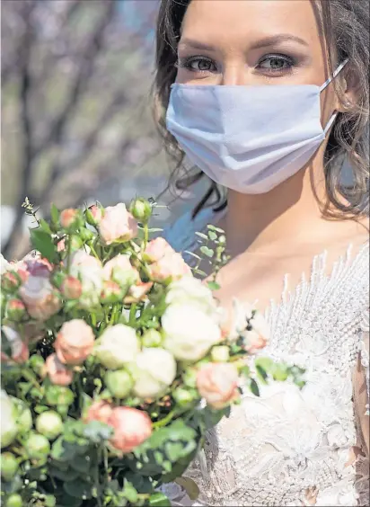  ??  ?? A bride in protective face mask. The Covid pandemic put many weddings on hold