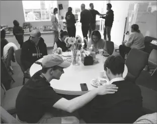  ?? GREGORY BULL/AP ?? VOLUNTEER SILAS BREEN (BELOW LEFT) from the Calvary Bible Institute, prays with David, from Ukraine, at San Diego Calvary’s shelter for Ukrainians arriving after crossing into the United States from Tijuana, Mexico on Friday, in Chula Vista, Calif.