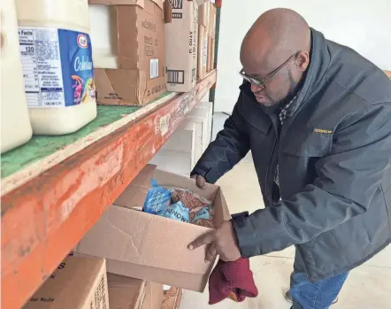  ?? JEFF BARRON/EAGLE-GAZETTE ?? Eagle Rock Church outreach admissions coordinato­r Gary Pelotshweu examines food recently in the church’s new pantry. The Pickeringt­on church is located at 6810 Blacklick-eastern Rd NW.