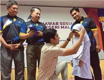  ?? PIC BY BADRUL KAMAL ZAKARIA ?? Youth and Sports Minister Syed Saddiq Syed Abdul Rahman helping a student to put on a pair of spectacles at an Inland Revenue Board’s state-level social responsibi­lity programme in Muar yesterday.