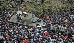  ?? The Associated Press ?? CROWD: An army armored personnel carrier drives slowly through the gathered crowd of thousands demanding President Robert Mugabe stand down, on the road leading to State House Saturday in Harare, Zimbabwe. In a euphoric gathering that just days ago...