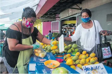  ?? Photo: Leon Lord ?? Market vendor Rosalyn Daveta, (left), selling her produce to customer Penina Dinalagi while practising social distancing and proper safety protocol at the Suva Municipal market on April 23, 2021.