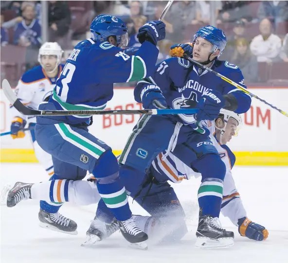  ?? — THE CANADIAN PRESS ?? Vancouver Canucks Alexander Edler, left, and Troy Stecher collide with Edmonton Oilers forward Connor McDavid during the Canucks’ 5-3 pre-season win Wednesday at Rogers Arena. Stecher, a Richmond native, had three points in his Canucks debut.