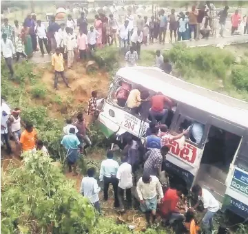 ??  ?? Onlookers and rescuers gather around a bus that crashed in Jagtial district in India’s southern Telangana state. — AFP photo