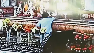  ??  ?? Taking what is not given:
A screen grab showing a man reaching for the Reclining Buddha statue on the altar at the PBA building in George Town.