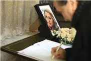  ??  ?? A man writes in the condolence book near a picture of Marinova.