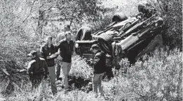  ?? JOHN GIBBINS/SAN DIEGO UNION-TRIBUNE ?? Border Patrol agents gather at the bottom of the ravine where a vehicle landed upside down after the driver tried to elude agents on Interstate 8 in March 2018. The vehicle left the roadway after losing control at more than 100 mph. The driver, who was not injured, tried to flee but was caught.