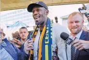  ??  ?? ERIK ANDERSON/REUTERS Eight-time Olympic champion Usain Bolt (C) reacts as he arrives at Sydney Airport ahead of his trial at the Central Coast Mariners soccer club in Sydney, Australia, on August 18, 2018.