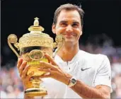  ?? CLIVE BRUNSKILL/GETTY ?? Roger Federer hoists the Wimbledon trophy Sunday after winning his record eighth title at the All England Club.