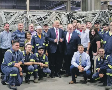  ?? JEFF SWENSEN / GETTY IMAGES ?? Then-Republican presidenti­al candidate Donald Trump gathers with workers in Monessen, Penn., last June. Nearly 1,000 Democrats in the town switched sides in the election and voted for Trump.