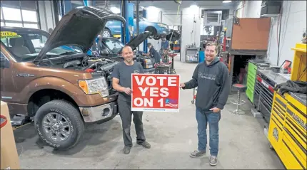  ?? CLIFF CLARK / SENTINEL & ENTERPRISE ?? Fitchburg auto repair service Kevin's Place is supporting voting yes on Question 1, known as the Right to Repair. Holding the sign are owner Kevin Michaud, left, and employee Anthony Williams. Behind them and working are Max Michaud and Andy Welch. Kevin's Place is located at 345 Boutelle St.