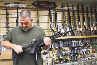  ?? Lea Suzuki / The Chronicle ?? John Parkin, owner of Coyote Point Armory in Burlingame, demonstrat­es the adjustable stock on a HK416 .22 LR rifle. The weapon is legal in California under terms of a revised ban on semiautoma­tic rifles.