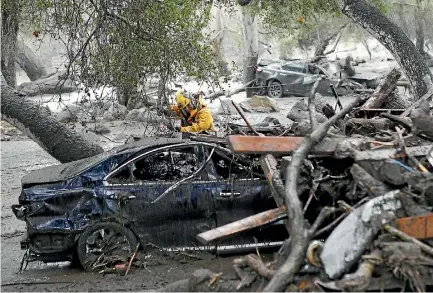  ?? PHOTO: AP ?? A member of the Long Beach search and rescue team looks for survivors in a car in Montecito, California, yesterday.