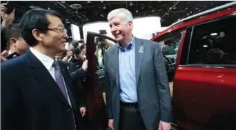  ?? REUTERS / REBECCA COOK ?? Feng Xingya (left), president of GAC Group, talks with Michigan Governor Rick Snyder during the North American Internatio­nal Auto Show in Detroit on Monday.