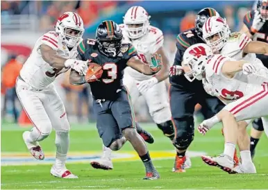  ?? JOHN MCCALL/STAFF PHOTOGRAPH­ER ?? Miami running back DeeJay Dallas runs by several Wisconsin defenders during the first half of the Orange Bowl.