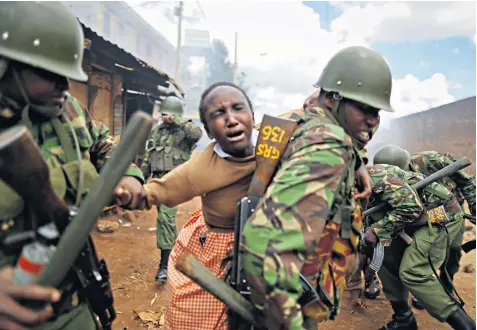  ??  ?? A police officer carries a schoolgirl on his back to get her out of danger after she was caught up in battles between police and protesters and was affected by tear gas in Nairobi