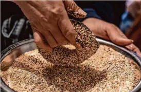  ?? Salgu Wissmath/The Chronicle ?? Poppy baker Sonia Hernandez coats a bagel in everything-flavored seeds and spices from Oaktown Spice Shop.