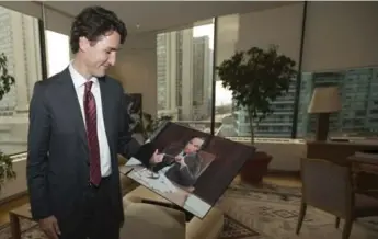  ?? RICK MADONIK/TORONTO STAR ?? Prime Minister Justin Trudeau smiles at a photo of his father, taken by retired Star photograph­er Boris Spremo, during his visit to the Toronto Star on Friday.