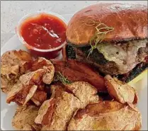  ?? ?? A grassfed local burger with smashed potatoes and housemade ketchup at Iron & Grass .