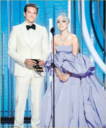  ?? NBCUnivers­al ?? BRADLEY COOPER and Lady Gaga present an award at the Golden Globes. Gaga’s dress had a 20-foot train.