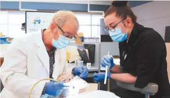  ??  ?? Dr. William Vansickle, and cnc dental student andrea nelson work on linda allen during the emergency Dental Outreach clinic on Friday morning.