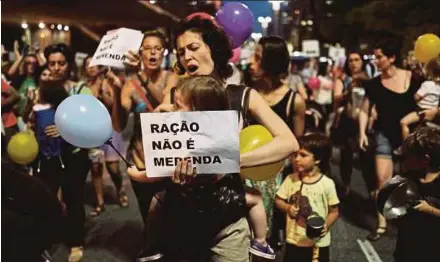  ?? PIC
REUTERS ?? A woman carrying her baby and holding a sign reading ‘Food pellets are not meals’ at a protest against plans to serve school meals made of reprocesse­d food pellets in Sao Paulo, Brazil, on Thursday.