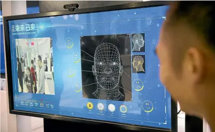  ?? AP ?? A man watches as a visitor tries out a facial recognitio­n display at a booth for Chinese tech firm Ping’an Technology at the Global Mobile Internet Conference in Beijing. Similar technology is incorporat­ed in the system being built in Australia.
