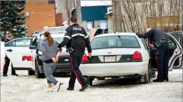  ?? Herald photo by Ian Martens ?? Lethbridge police take one of a number of people into custody while executing a search warrant at a downtown apartment building Thursday that resulted in two people being charged with drug-related offenses. @IMartensHe­rald