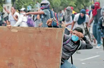  ??  ?? Un manifestan­te usa una resortera para lanzar de piedras contra los elementos de la policía antimotine­s durante la protesta contra las reformas al Seguro Social, en Managua, Nicaragua.