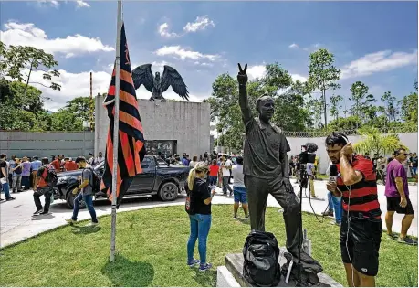  ?? CARL DE SOUZA / GETTY IMAGES ?? Journalist­s remain near the flag of Brazilian soccer club Flamengo that was placed at half-mast at the team’s training center after the sleeping quarters there caught fire Friday, killing 10 people, including several budding stars.