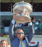  ?? EDUARDO MUNOZ ALVAREZ/AP ?? Sir Winston trainer Mark Casse lifts up the Belmont Stakes trophy Saturday. He won the Preakness with War of Will.