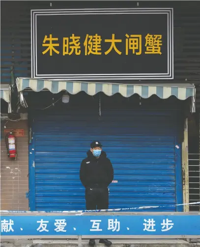  ?? HECTOR RETAMAL / AFP via Gett y Images Files ?? A guard stands outside the seafood market where the coronaviru­s was detected in Wuhan. China now claims to have snuffed out local transmissi­on of COVID-19.