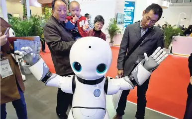  ?? AP ?? Visitors look at a robot during World Robot Conference in Beijing, China.