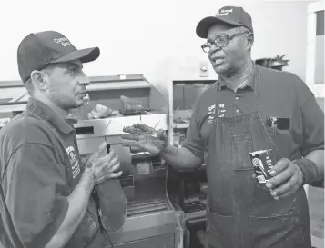  ?? LIZ DUFOUR, THE CINCINNATI ENQUIRER ?? Clarence Howell, 78, instructs Bassam Osman, 36, at Howell’s shoe repair store in Pleasant Ridge, Ohio. Osman is a Syrian refugee who came to Cincinnati with his family in July 2016.