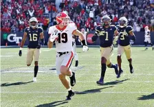  ?? Curtis Compton/Atlanta Journal-Constituti­on via AP ?? ■ Georgia tight end Brock Bowers looks over his shoulder at Georgia Tech defenders as he heads to the end zone for a touchdown reception during the second quarter of an NCAA football game Saturday in Atlanta.