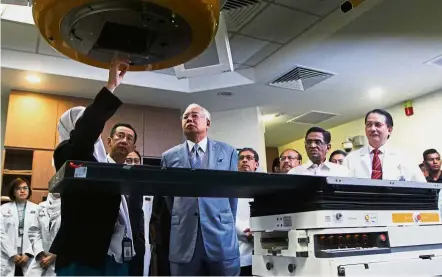  ??  ?? Hi-tech equipment: Science physic chief officer Mahzom Pawanchek showing Najib how the cancer treatment machine works after the official opening of the National Cancer Institute. With them are Dr Subramania­m and Dr Noor Hisham (right) and medical...