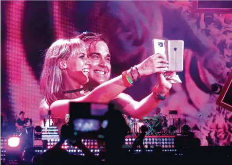  ??  ?? Was für ein Moment: Brigitte Dempf auf der Bühne mit ihrem Idol Robbie Williams. So was muss natürlich mit dem Handy festgehalt­en werden.