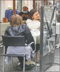  ?? (AP/Gregorio Borgia) ?? People enjoy a hot drink at an outdoor seating area of a cafe in Rome. Italy began gradually opening Monday after six months of rotating virus lockdowns.