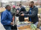  ?? Post-Gazette ?? Joann Brown, North Side, receives a bag of grapes from Cameron Clarke, Homestead, during the Greater Pittsburgh Community Food Bank walk-in food distributi­on on Nov. 12 at Pittsburgh King School on the North Side.